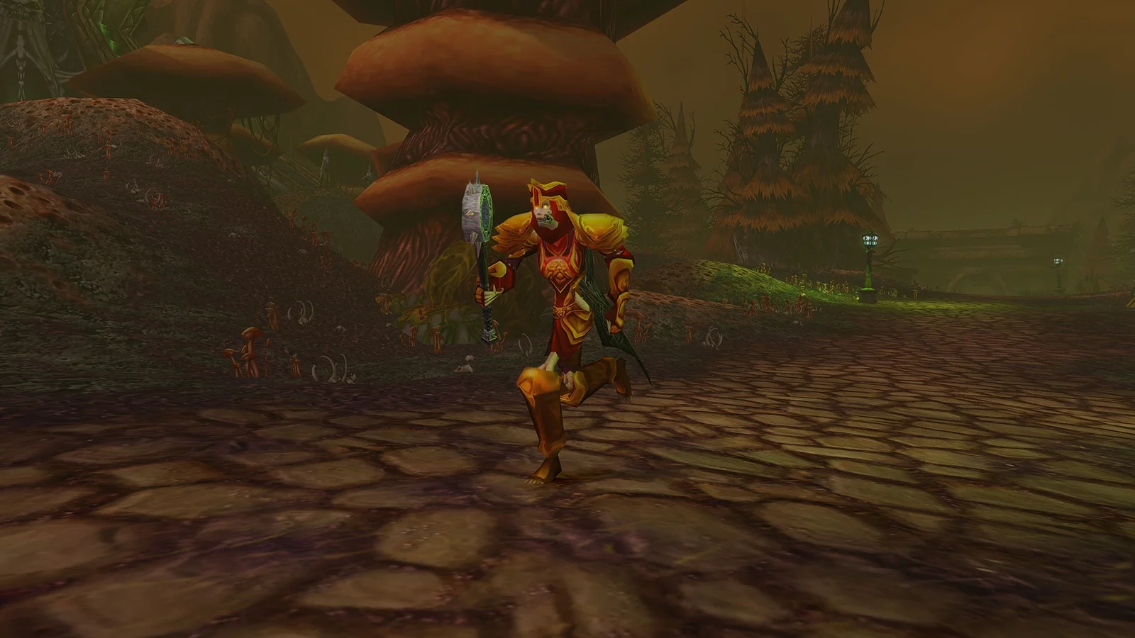 A Forsaken character in gold and red plate armor carrying a hammer along a gloomy forest path.